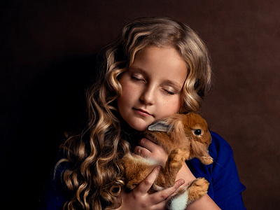 The girl is holding a red rabbit in her hands.