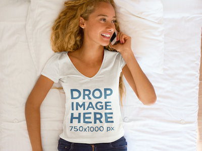 Young Woman Lying in Bed Using an iPhone T-Shirt Mockup