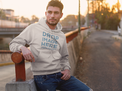 Hoodie Mockup of a Man Standing Next to a Bridge