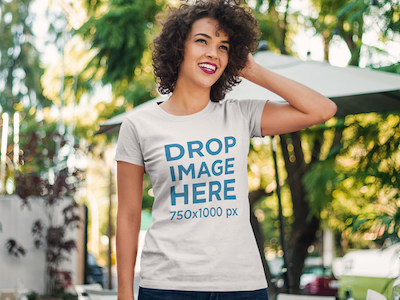 Curly-Haired Woman Standing Outside a Cafe T-Shirt Mockup digital marketing mockup generator mockup template mockup tools stock photo mockup stock photo template t shirt mockup t shirt mockup generator t shirt mockup template t shirt template visual marketing campaign web marketing