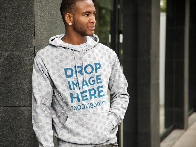 Black Man in a Hoodie Mockup Leaning Against a Wall hoodie hoodie mockup hoodie mockup generator hoodie mockup template hoodie stock photo hoodie template image marketing photorealistic mockup web marketing