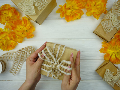 Women's hands tie a bow on a gift