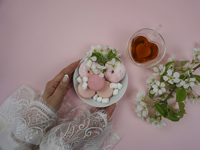 Women's hands put sweets and tea on the table on a pink backgrou typography