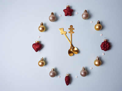 Teaspoons and Christmas balls are laid out in the form of a cloc design