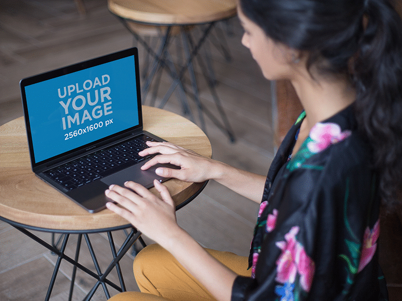 Woman Working On A Macbook Mockup Over A Coffee Table digital mockup macbook macbook air macbook pro macbook pro retina mockup mockup generator ui ux