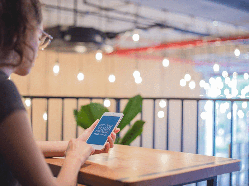 Mockup of a Girl Using a Rose Gold iPhone 7 Over a Wooden Table app design template iphone mockup