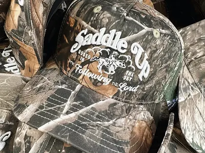 Saddle Up • Camo Hats apparel christian cowboy embroidery horse howler hunting illustration merch nature outdoors realtree rodeo seager sendero sky typography western